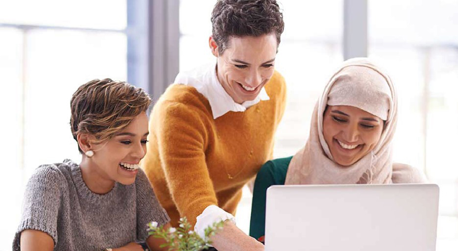 Drei Junge Frauen arbeiten in einem hellen Büro freunlich zusammen